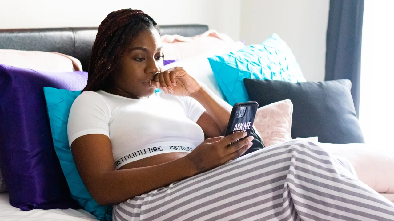 Femme assise sur le canapé en regardant son téléphone portable