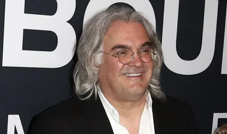 Paul Greengrass, British director known for his realistic and intense style, with a smiling expression.