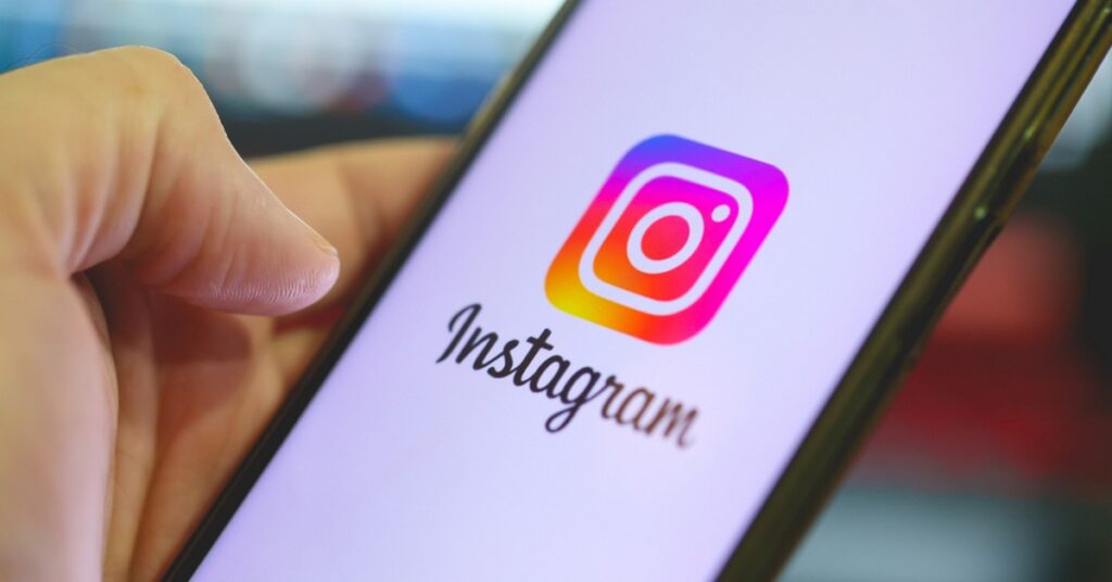 Instagram アプリが開いた携帯電話を手に持つ人