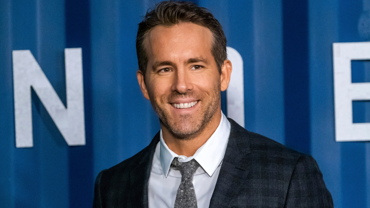 Ryan Reynolds sonriendo con ropa formal